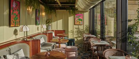 Un espace intérieur accueillant, avec des canapés confortables, des tables rondes et des chaises en osier.