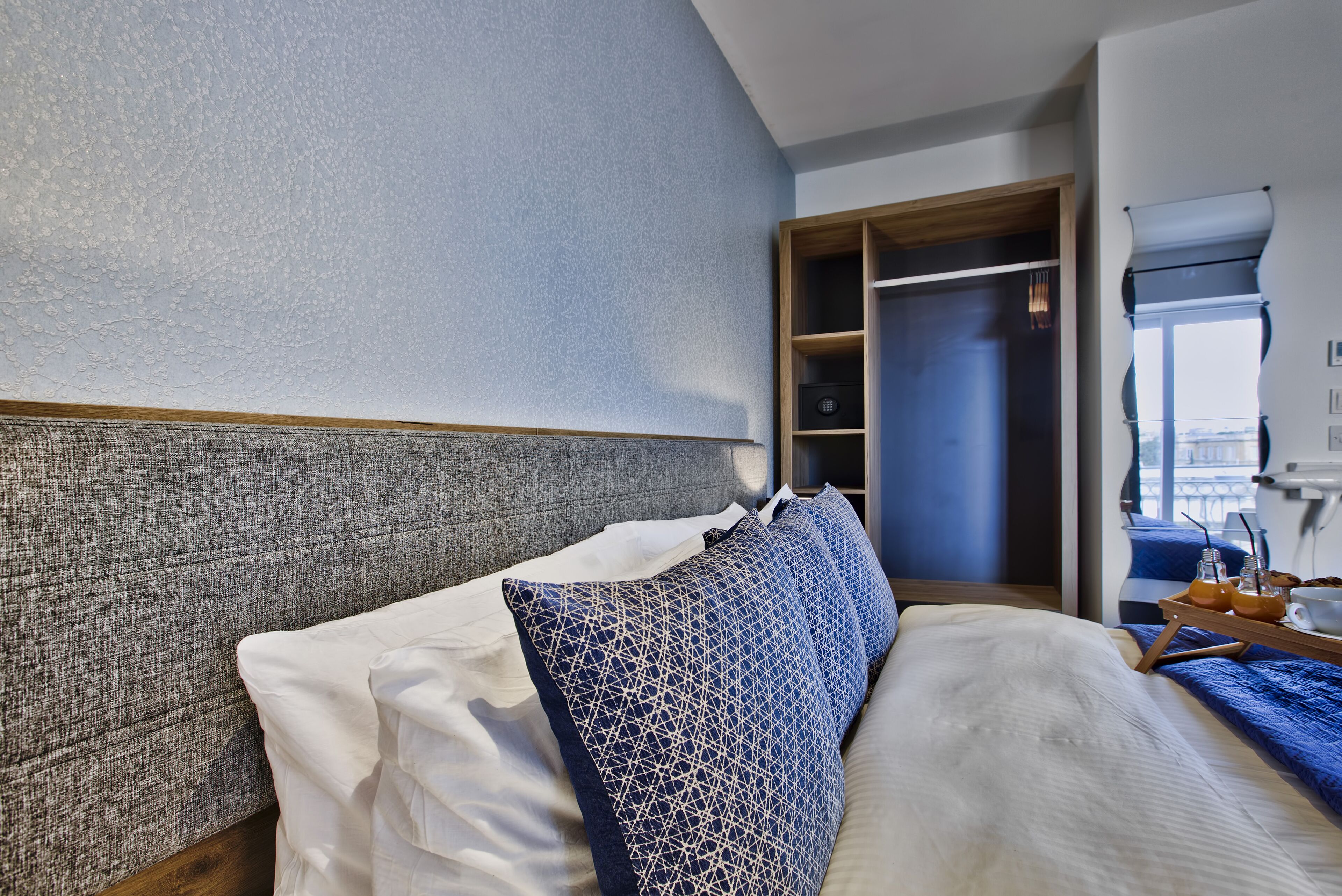 A modern hotel room with a large bed, a wardrobe, and a window with a view.