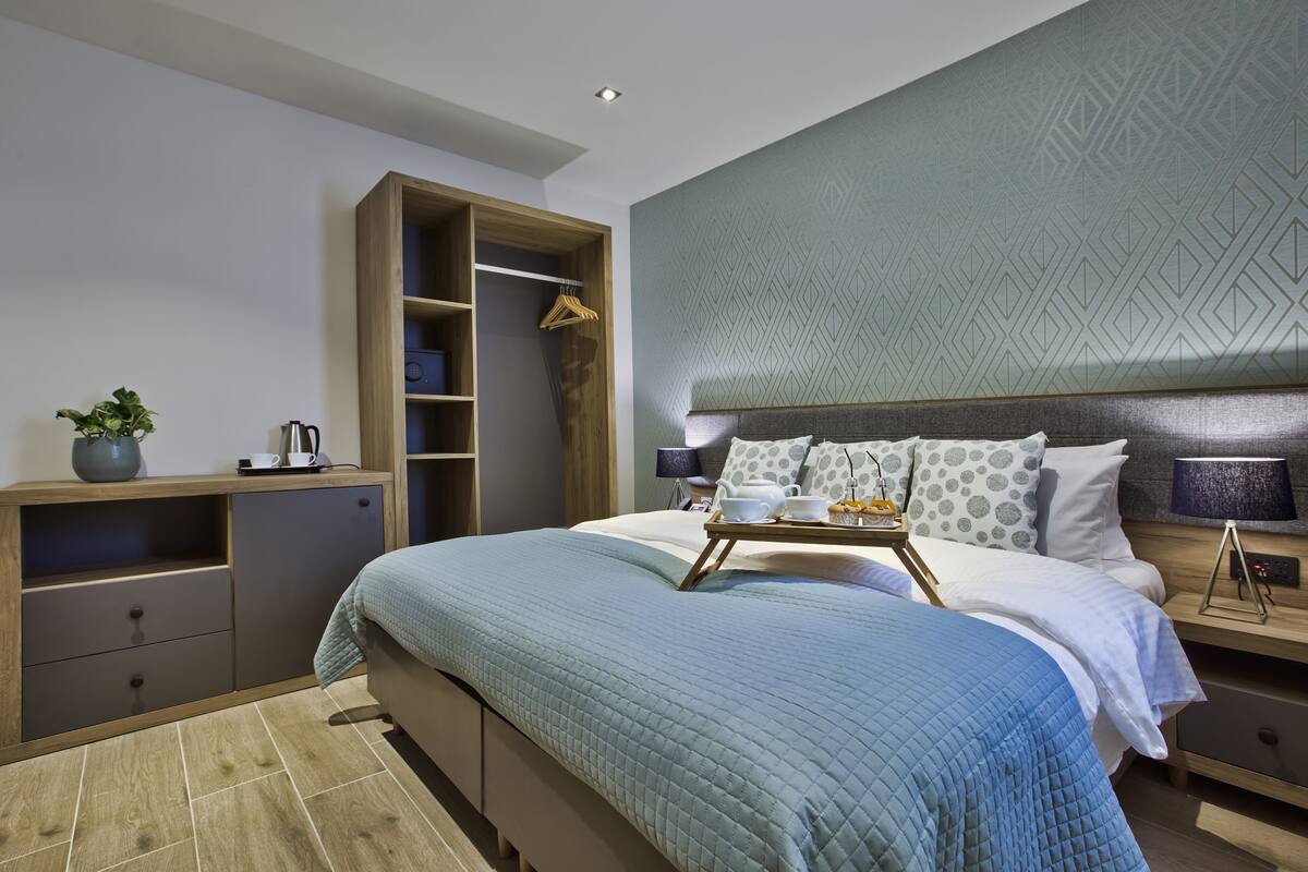 Une chambre moderne avec un lit, des tables de chevet, une armoire et un plateau contenant des articles pour le petit-déjeuner.