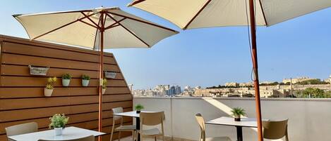 Un espace extérieur aménagé avec des tables, des chaises, de grands parasols et des plantes en pot.