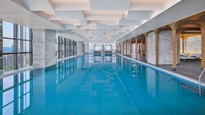 Una piscina interior moderna con vistas despejadas del horizonte urbano a través de amplios ventanales.