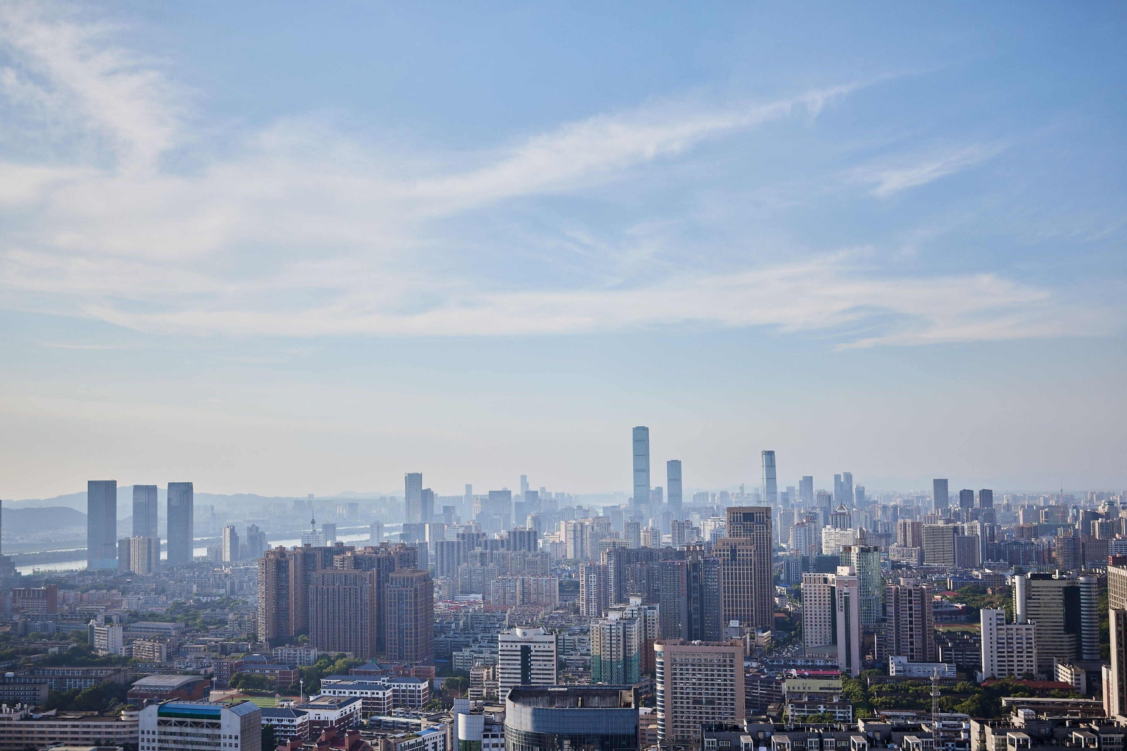 A cityscape with numerous high-rise buildings, a river in the background, and a clear sky.