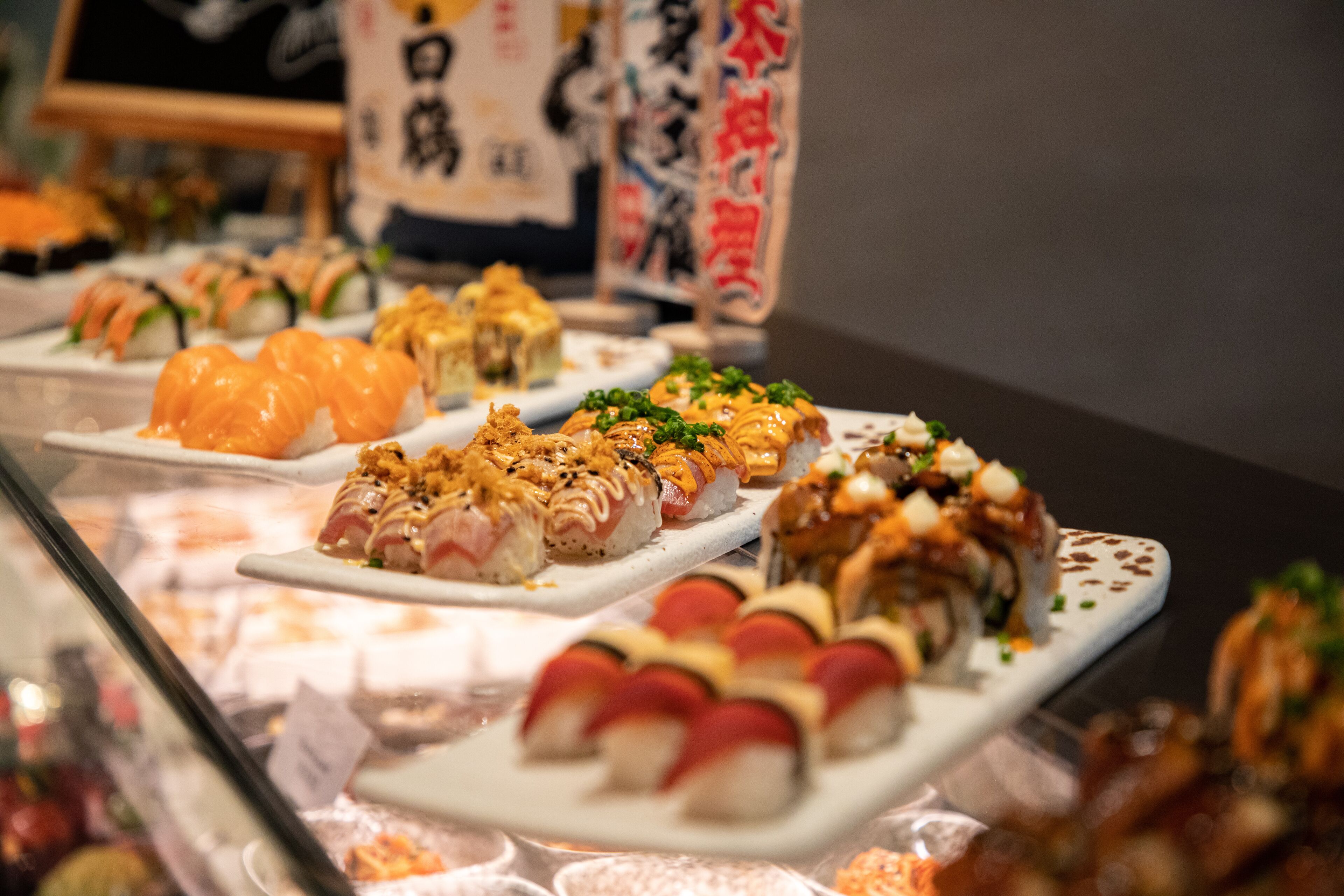 A variety of sushi dishes displayed on plates in a restaurant setting.