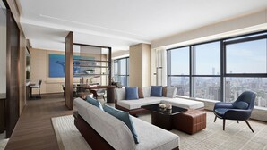 Una sala de estar moderna con un sofá grande, una mesita de centro y vistas a la ciudad a través de amplios ventanales.