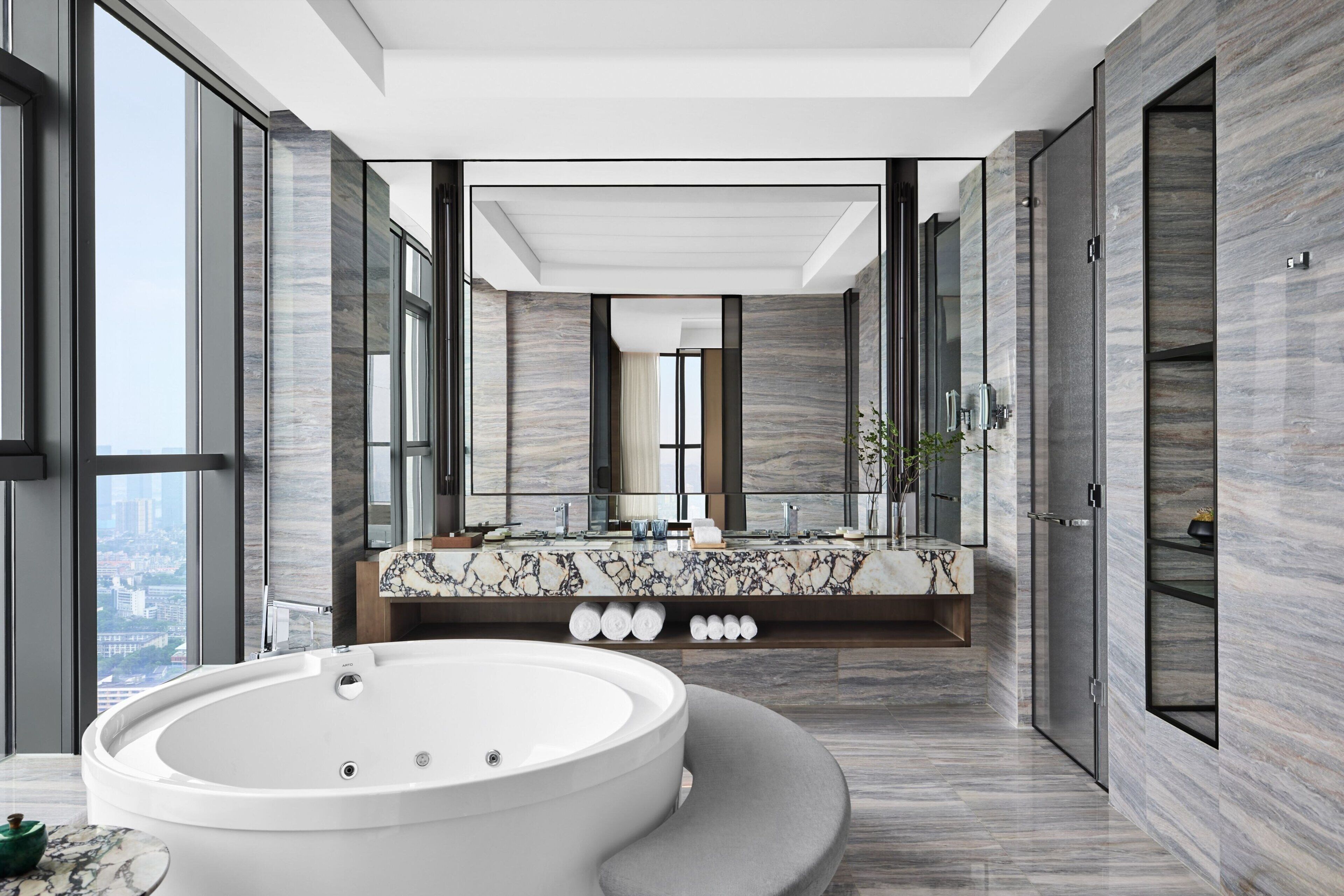 Un baño moderno con una bañera grande, un tocador de mármol y un espejo amplio.
