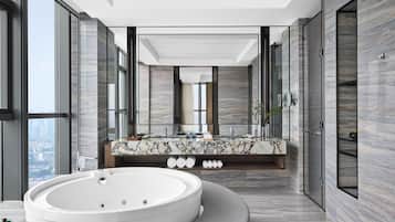 Un baño moderno con una bañera grande, un tocador de mármol y un espejo amplio.