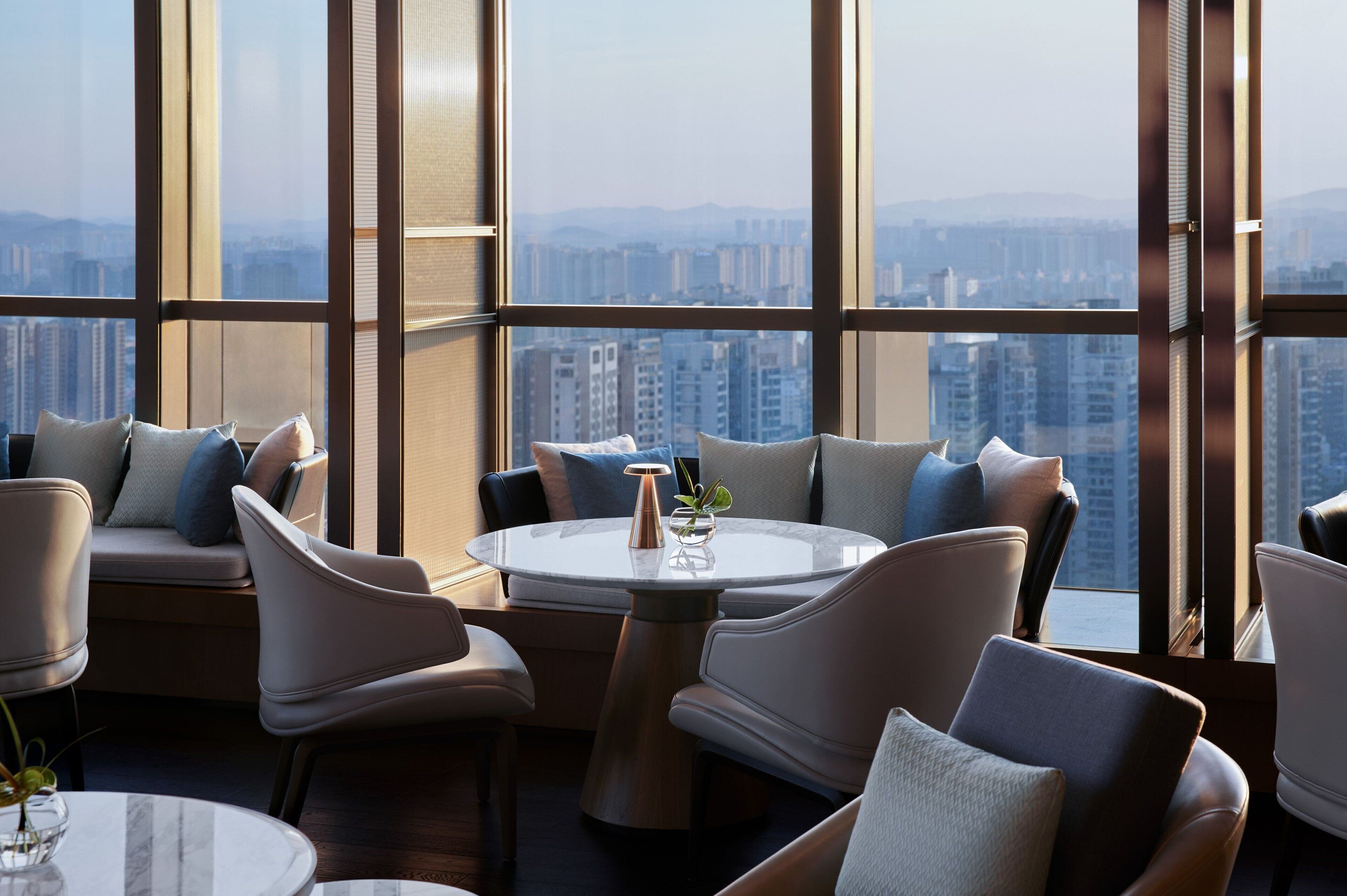 Un interior moderno con una mesa redonda y sillas, ventanas amplias que ofrecen vistas a la ciudad.