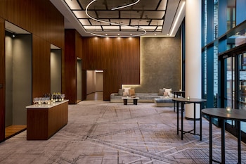 A modern kitchen with wooden cabinets, a dining area with a glass table, and a view of buildings through large windows. at Washington Marriott Capitol Hill