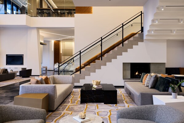A spacious living area with a staircase, modern furniture, and a fireplace.