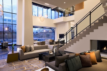 A modern bar area with a marble countertop, bar stools, and a view of the cityscape at dusk. at Washington Marriott Capitol Hill