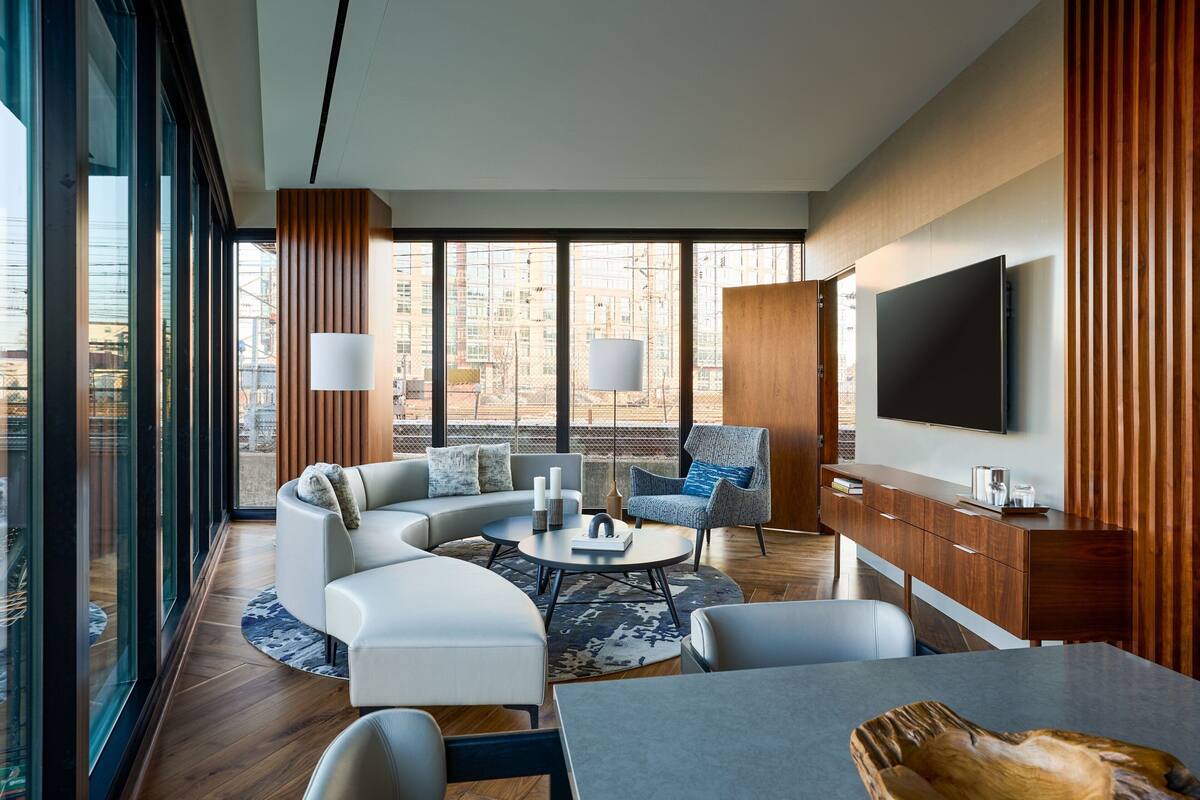 A modern living room with a curved sofa, a coffee table, and a TV mounted on the wall.