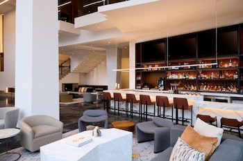 A modern hotel lobby with a central seating area, wooden paneling, and a chandelier. at Washington Marriott Capitol Hill