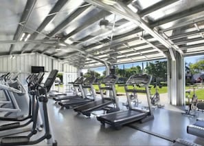 Een overdekte fitnessruimte met loopbanden en trainingsapparatuur.