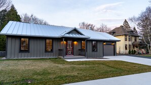 A modern two-story house with a metal roof, a front porch, and a garage. - 𝗨𝗻𝗶𝗾𝘂𝗲 𝗦𝘁𝗮𝘆 at the Carriage Haus (Manitowoc)