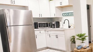 A modern kitchen with white cabinets, stainless steel appliances, and a sign reading 'BEACH HOUSE'. - ☀️Newly renovated cottage at the coast….60 second walk to the beach🌊 (North Topsail Beach)