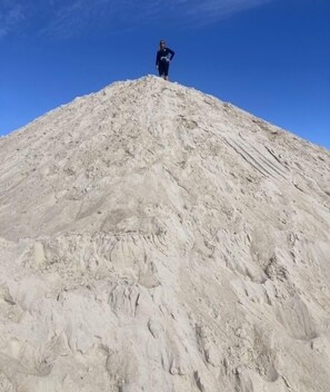 A person standing on a large pile of sand.