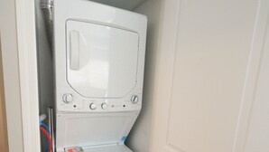 Une petite buanderie équipée d’un lave-linge et d’un sèche-linge, avec une porte et un plancher en bois.