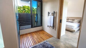 Une chambre moderne avec un plancher en bois, une porte vitrée donnant sur l’extérieur, un lit avec une literie blanche et un petit tapis.