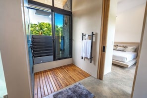 A modern room with a wooden floor, a glass door leading outside, a bed with white bedding, and a small rug.