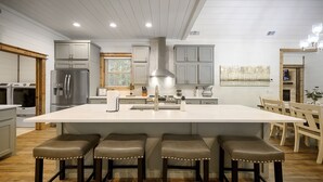 A modern kitchen with a large island, bar stools, and built-in appliances. - ✨Live in the Moment🔥Fireplaces 💦Hot Tub 🎮Games 🛏️Luxury Suites 🌲Outdoor Fun (Broken Bow)