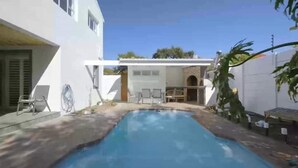 A swimming pool with a patio area, a white building, and a brick structure with outdoor seating. - Mount View. Luxury 3 bed villa with pool (Cape Town)