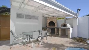 An outdoor patio with a brick oven and a table with chairs. - Mount View. Luxury 3 bed villa with pool (Cape Town)