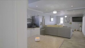 A modern kitchen with a refrigerator, stove, and microwave. There is a dining area with a sofa and a table. - Mount View. Luxury 3 bed villa with pool (Cape Town)
