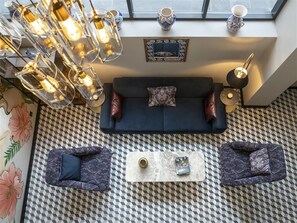 A modern living room with a sofa, two poufs, a coffee table, and a patterned floor. - Radisson Hotel Hagia Sophia a Member of Radisson Individuals (Istanbul)