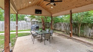 An outdoor patio with a covered seating area, a table, and chairs.