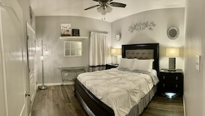 A bedroom with a bed, bedside tables, a ceiling fan, and wall decorations.
