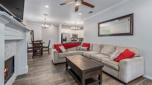 A living room with a fireplace, a sectional sofa, a wooden coffee table, and a ceiling fan.