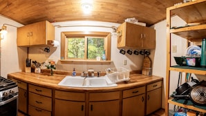 A compact kitchen with wooden cabinets, a built-in stove, and a window with a view of greenery.
