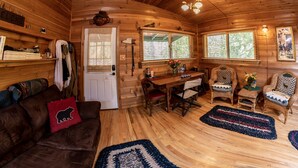 A cozy cabin interior with a wooden interior, a dining area with a table and chairs, and a door with a window.