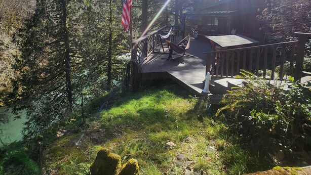 A deck with outdoor furniture, an American flag, and a forested backdrop.