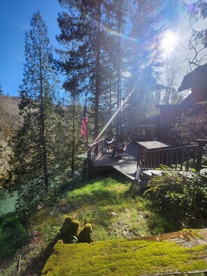 A deck with outdoor furniture, an American flag, and a forested backdrop.