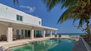 A modern resort with a pool, outdoor seating, and a view of the ocean. - Casa Mega - Yucatan Home Rentals (Chicxulub Puerto)
