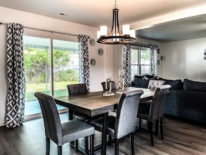 Enjoy meals in this dining area with a wooden table and six chairs, surrounded by a large window and a cozy seating area.