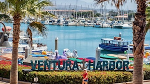 A marina with boats, a sign reading "VENTURA HARBOR", and a woman walking.