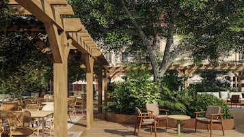 An outdoor patio area with wooden pergolas, wicker furniture, and potted plants.