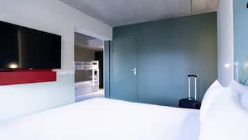 Quarto de hotel moderno com uma cama grande, televisão de tela plana na parede, guarda-roupa e mala.