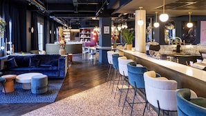 A modern bar area with a bar counter, seating, and a mix of bar stools and chairs. - ibis Styles Le Touquet (Le Touquet-Paris-Plage)