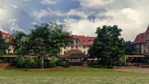A courtyard with a gazebo, surrounded by trees and buildings with red roofs. - ibis Styles Le Touquet (Le Touquet-Paris-Plage)
