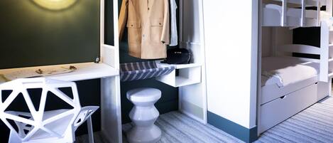 Habitación pequeña con una cama litera, un escritorio con silla, un perchero y un taburete.