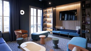 A modern living room with a sofa, armchairs, a coffee table, and a TV. - ibis Styles Le Touquet (Le Touquet-Paris-Plage)