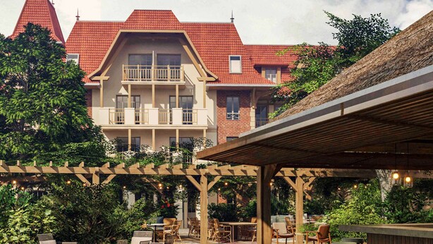 A wooden deck with outdoor seating, surrounded by lush greenery and a building with a red-tiled roof. - ibis Styles Le Touquet (Le Touquet-Paris-Plage)