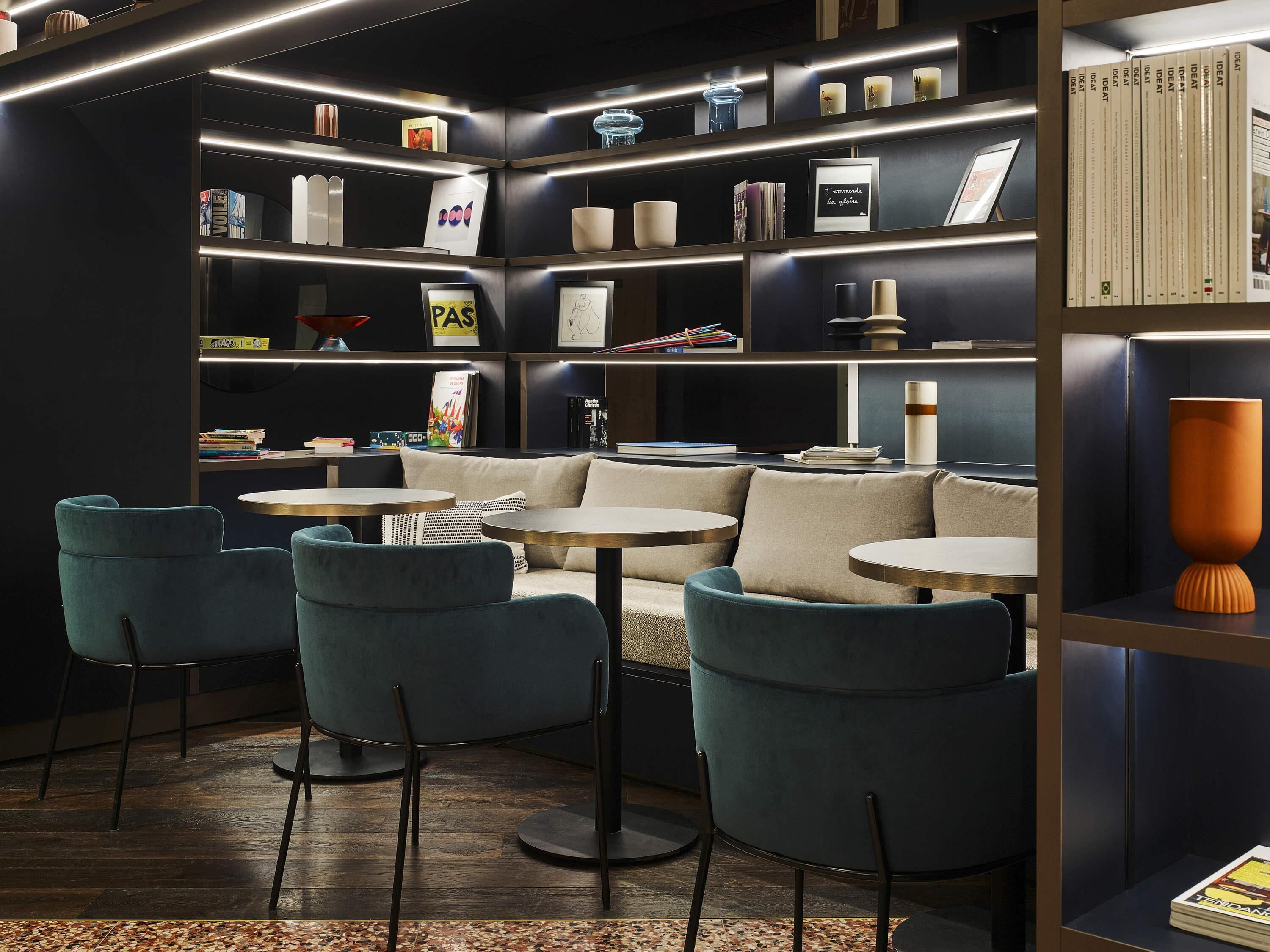 A modern library with bookshelves, a sofa, and round tables.