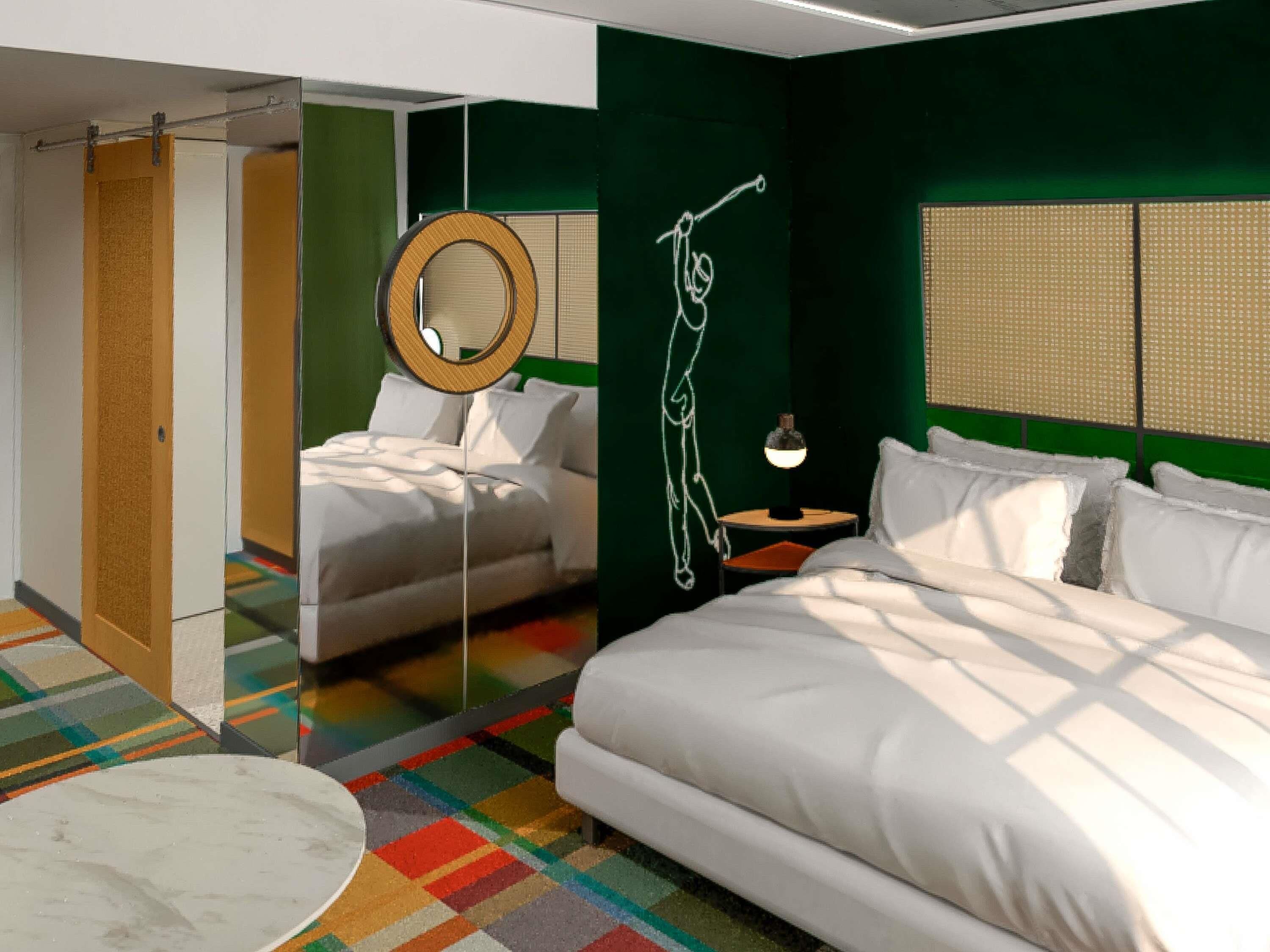 Ein modernes Schlafzimmer mit einem Bett, einem Nachttisch mit Lampe, einem Spiegel und einem farbenfrohen Streifen Teppich.