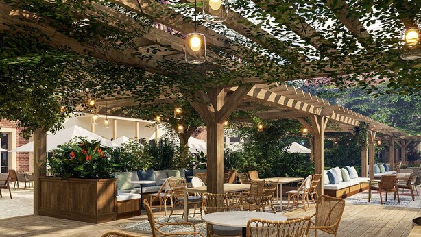 Un patio al aire libre con mobiliario de mimbre, una pérgola con luces colgantes y una terraza de madera.