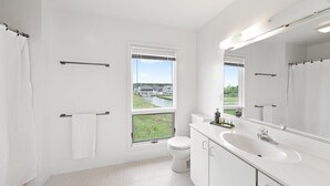 A modern bathroom with a large window, a white sink, and a toilet. - Serene Sunrise & Shimmering Skyline. 5 Star Hosts (Ocean City)