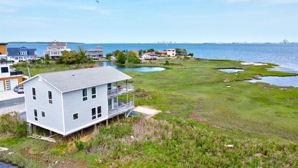 A coastal house with a balcony, a grassy area, and a view of the sea. - Serene Sunrise & Shimmering Skyline. 5 Star Hosts (Ocean City)